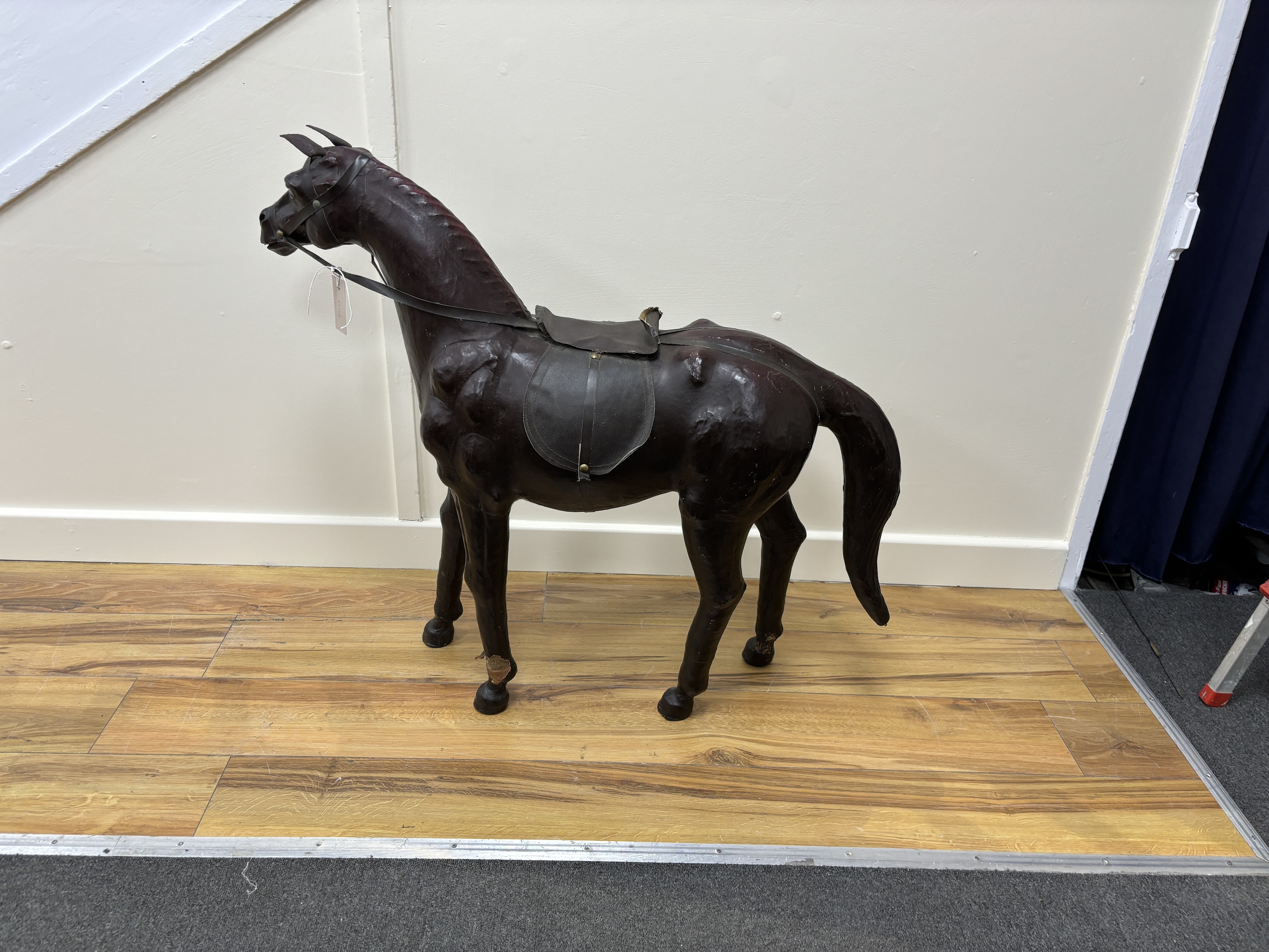 A burgundy leather covered model of a horse with faux leather tack, height 76cm